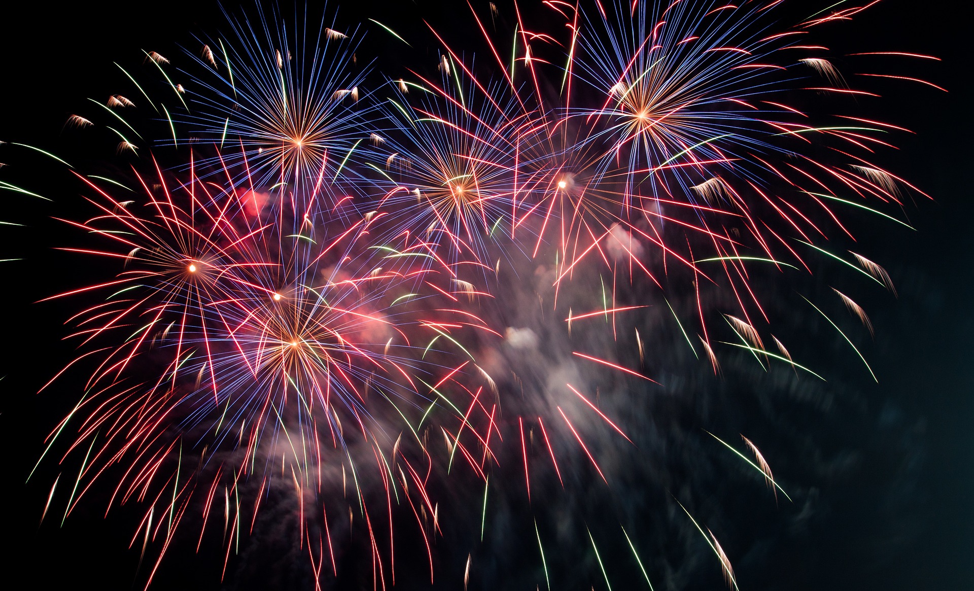 Red, blue, and gold fireworks exploding against the night sky