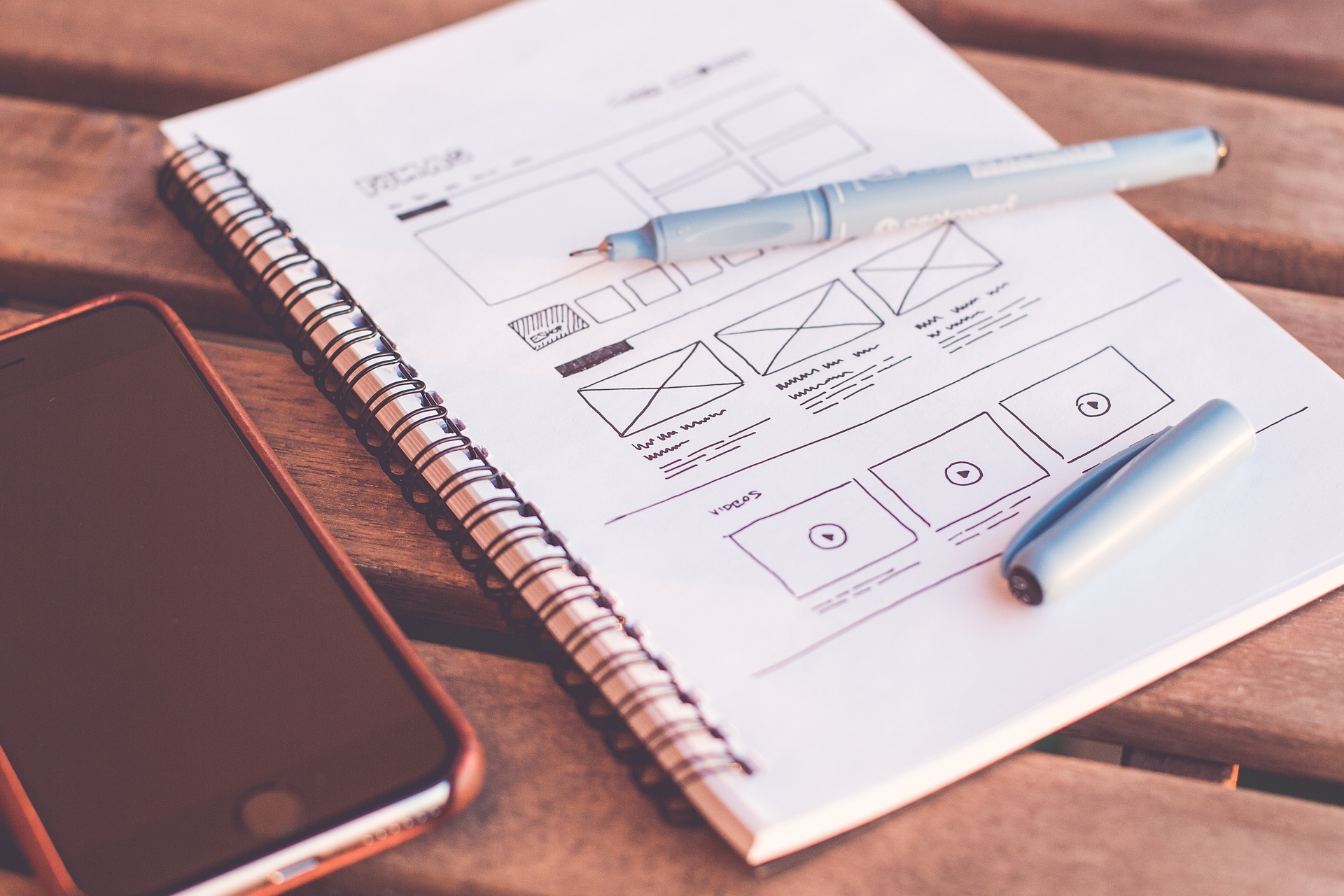 A sketchbook page with hand-drawn website wireframes, markers, and a smartphone