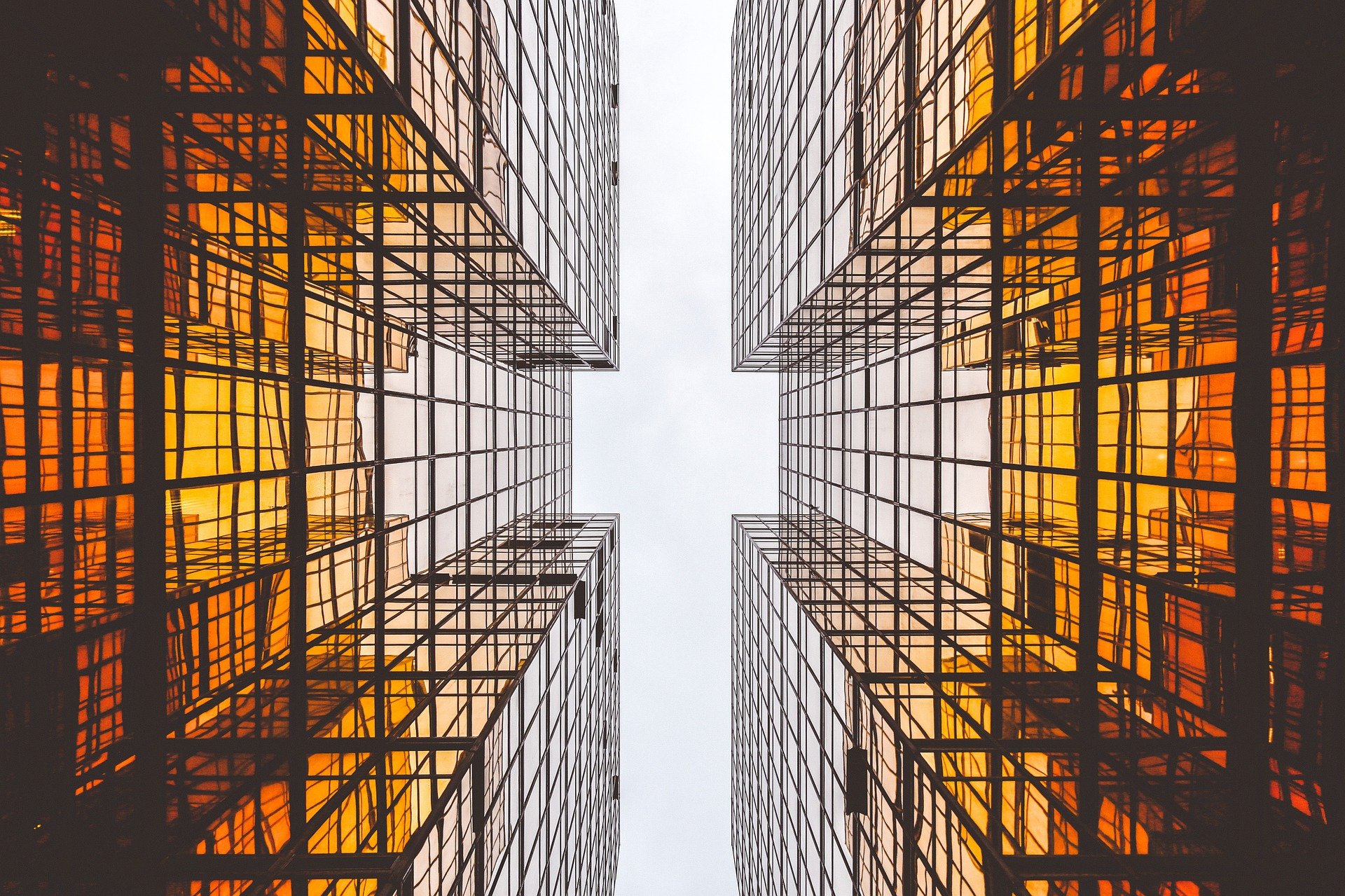 A low-angle view of two tall buildings with reflective glass facades creating a geometric pattern